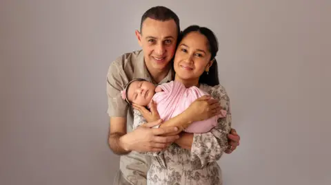 Darya Novikova/PA Real Life Bella in a pink blanket, being held by her parents