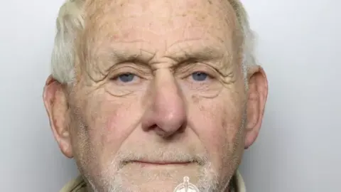 Dyfed Powys Police A close-up police shot of 72-year-old Flavin looking straight into camera with white, receding hair and untidy white stubble