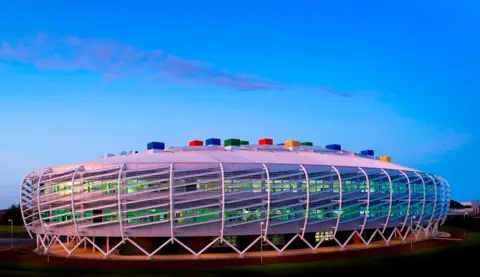 Monkseaton High School. It is a colourful, oval-shaped futuristic-looking building with multi-coloured bricks on its roof.