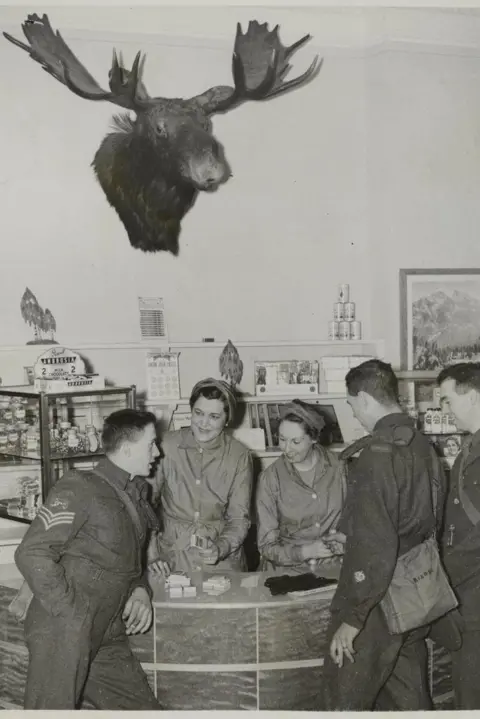 Getty Images A black and white photo of three soldiers and two women at the Canadians New Beaver Club