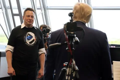 Reuters Musk facing the camera as we see the back of Trump