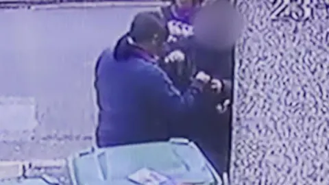 Tuyet van Huynh A grainy still from CCTV footage showing Tuyet’s mother handing over a plastic bag containing her valuables to be blessed by a scammer.