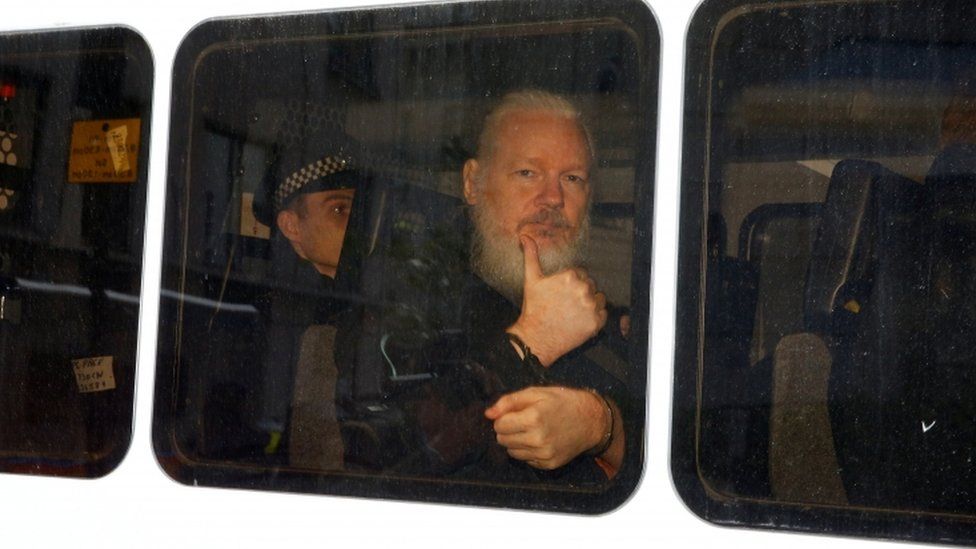 Assange gestures with a thumbs up after he was arrested by Met Police officers at the Ecuador Embassy in London