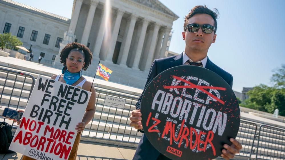 Two people protest against abortion in front of the Supreme Court building.