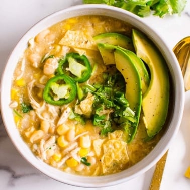 Healthy white chicken chili in bowl with avocado, cilantro and jalapeno.