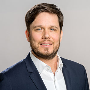 Headshot of Prof. Dr. Andreas Pondorfer, a middle aged man smiling on a simple gray background.