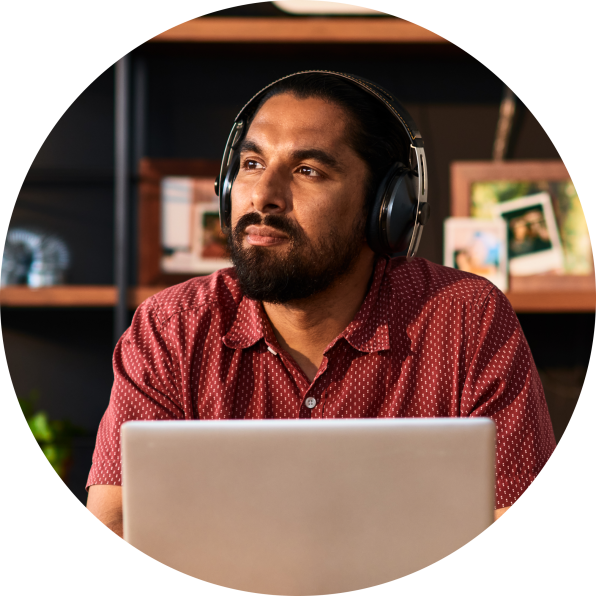 Homem trabalhando em um laptop enquanto usa fones de ouvido.