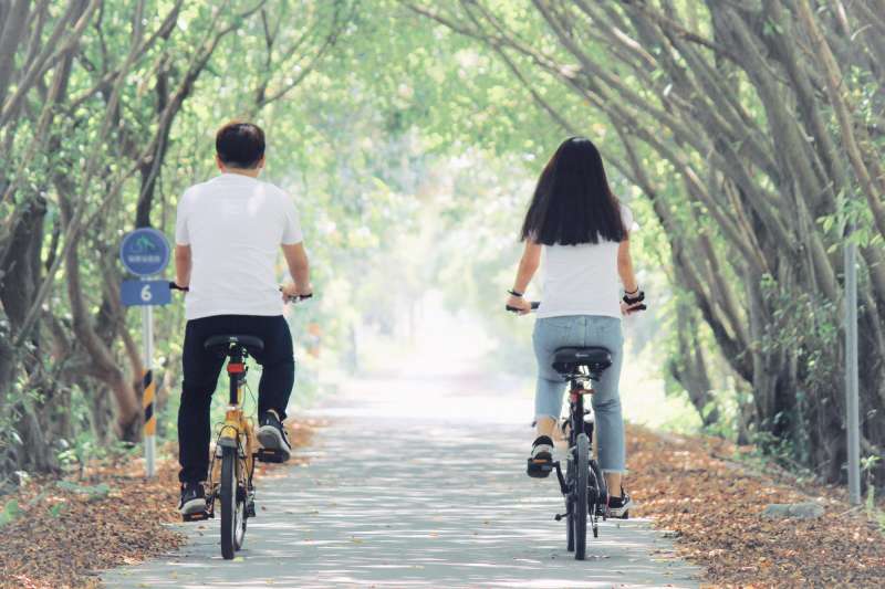 隘寮溪鹽埔段堤防自行車道有一段綠色隧道，二側夾道濃密的綠蔭有如日本卡通「龍貓」裡的秘境。（屏東縣政府提供）