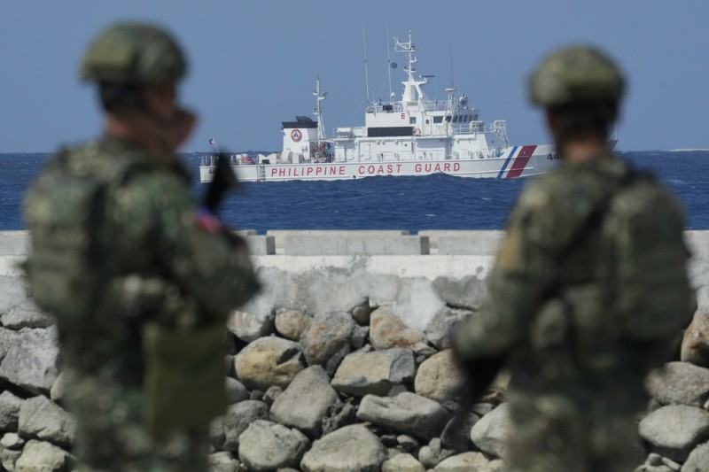 中業島（Pag-Asa）上的菲律賓軍人與正在海上巡弋的菲律賓海警。（美聯社）