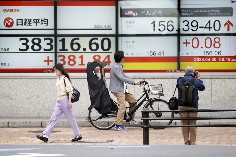 2024年4月30日。東京一家證券公司，人們經過顯示日本日經 225 指數（左）和美元/日圓兌換率的電子股票板。（美聯社）