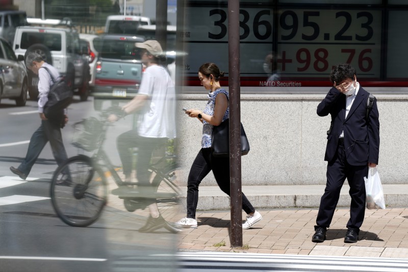 2024年6月24日。東京一家證券公司外，一個人在烈日下站在顯示日本日經 225 指數的電子股票板前。（美聯社）