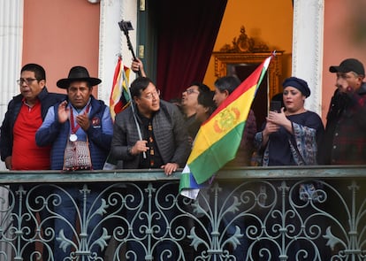 El presidente de Bolivia, Luis Arce, sostiene una bandera mientras se asoma a un balcón después de "denunciar la movilización irregular" de algunas unidades del ejército del país.