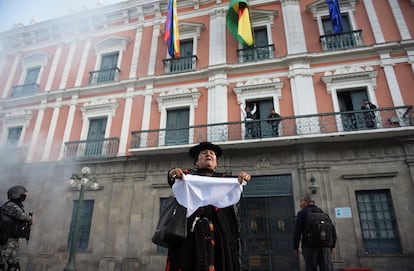 Una mujer sostiene una tela blanca frente al palacio de Gobierno.