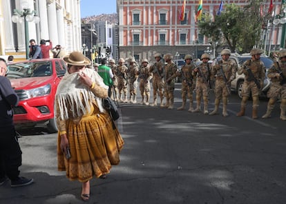 Una mujer se protege del humo frente a unos militares formados frente a la sede del Gobierno de Bolivia.