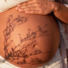 Naked belly of pregnant woman with shadow of plant. Maternity, pregnancy and motherhood concepts