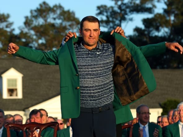 Le numéro un mondial, l'Américain Scottie Scheffler, vainqueur du Masters, enfile la traditionnelle veste verte, remise par le précédent vainqueur, le Japonais Hideki Matsuyama, le 10 avril 2022 à Augusta (Géorgie