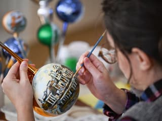 Une femme en train de peindre une décoration de Noël (illustration)