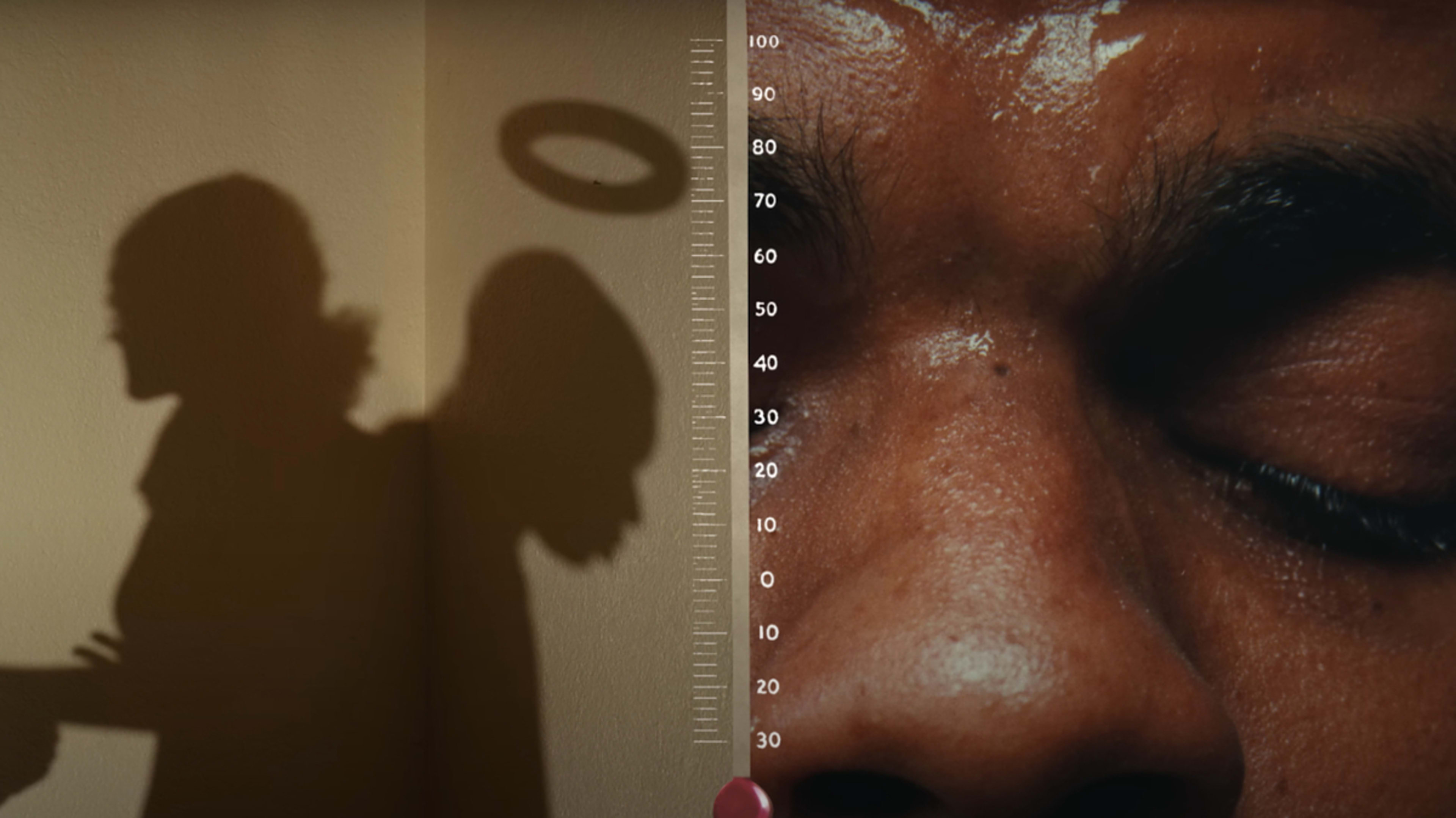 Close-up of a person's face with their eyes closed, and the shadow of someone holding a halo over their head beside a height measurement chart