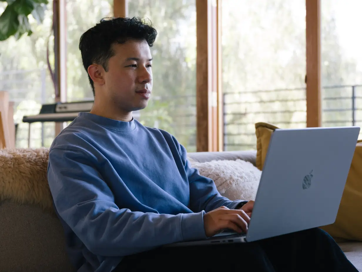 Person using 1Password’s password manager to securely login via his Mac laptop while working from home. 
