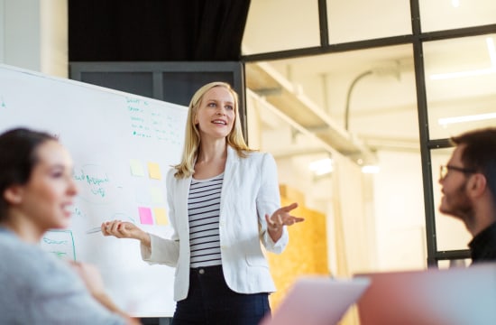 Marketing professional in front of whiteboard brainstorming with team