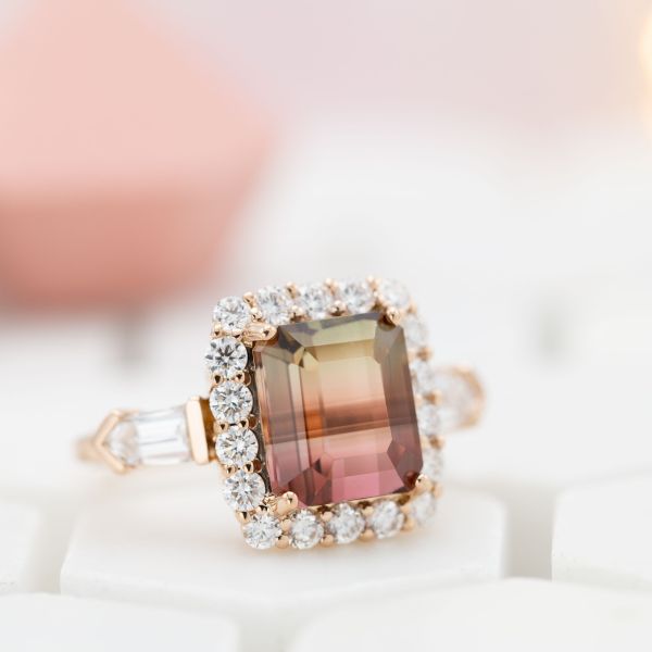 Watermelon tourmaline ring with a diamond halo and bullet cut diamond side stones.