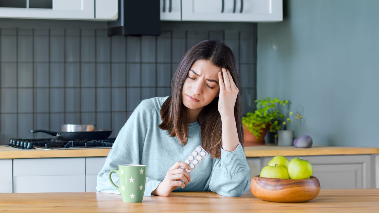 young woman holding acid reflux medication with migraine