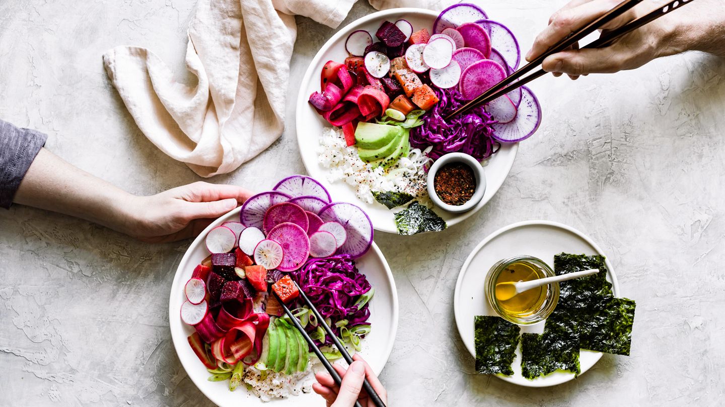 flatlay of two vegetarian poke bowls with hands