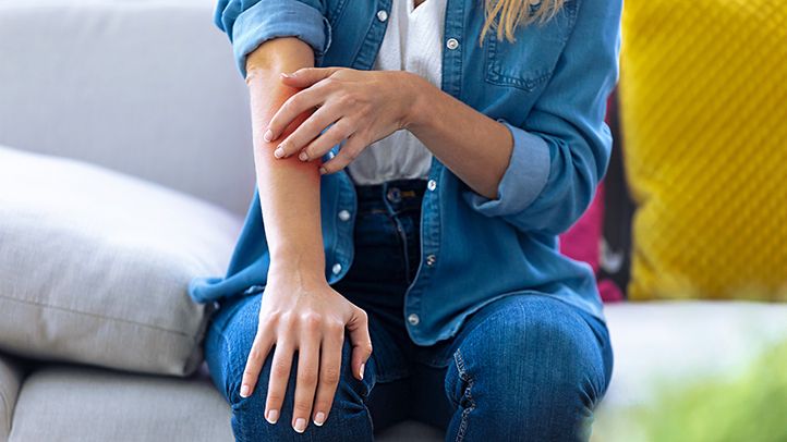 woman scratching arm on couch 