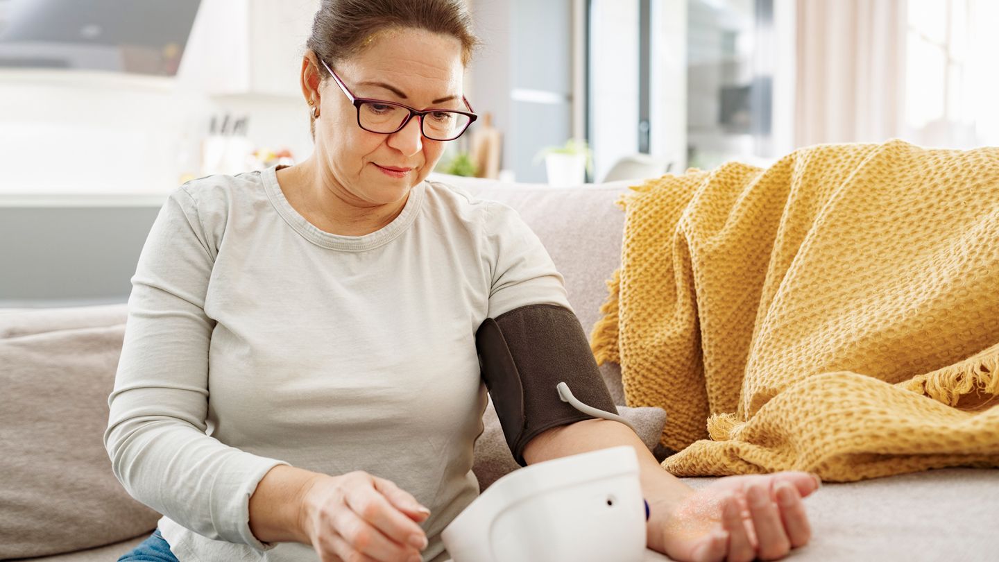 woman with psoriasis taking blood pressure at home