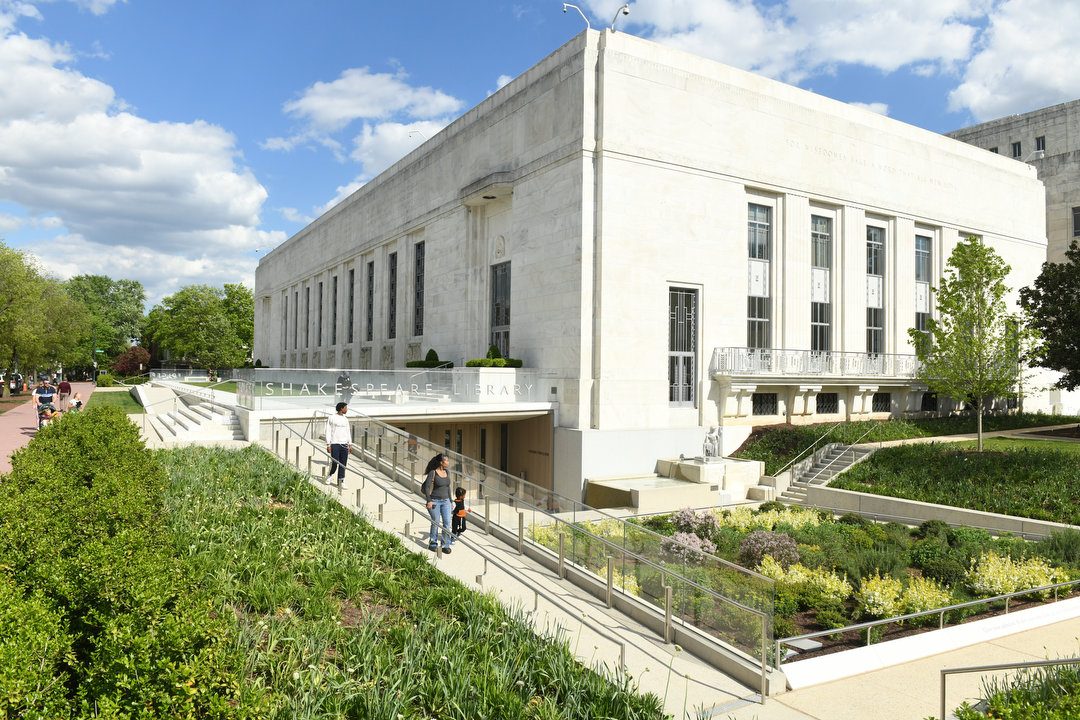 a ramp leading down through green gardens and past the Puck fountain to the Folger building west entrance, on a sunny day