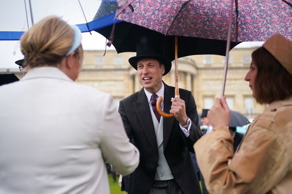 Smiling Prince William shaking guest's hand at Buckingham Palace