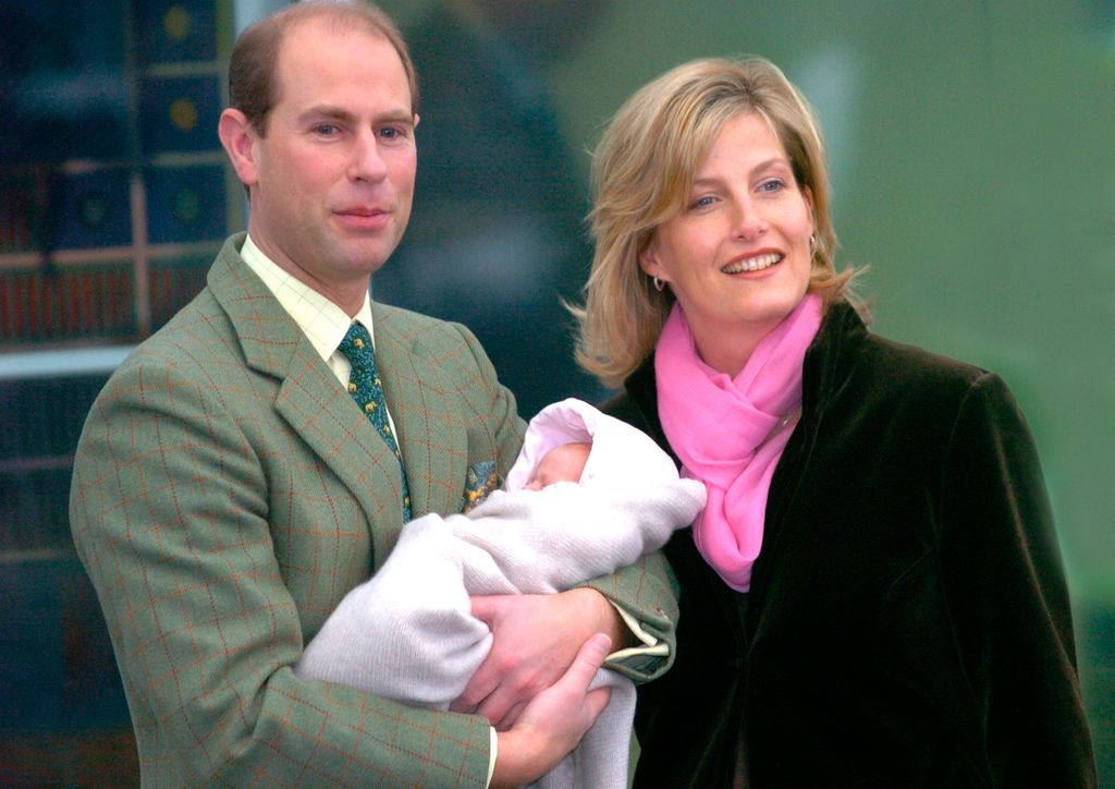 Prince Edward holding a baby girl while stood with Duchess Sophie