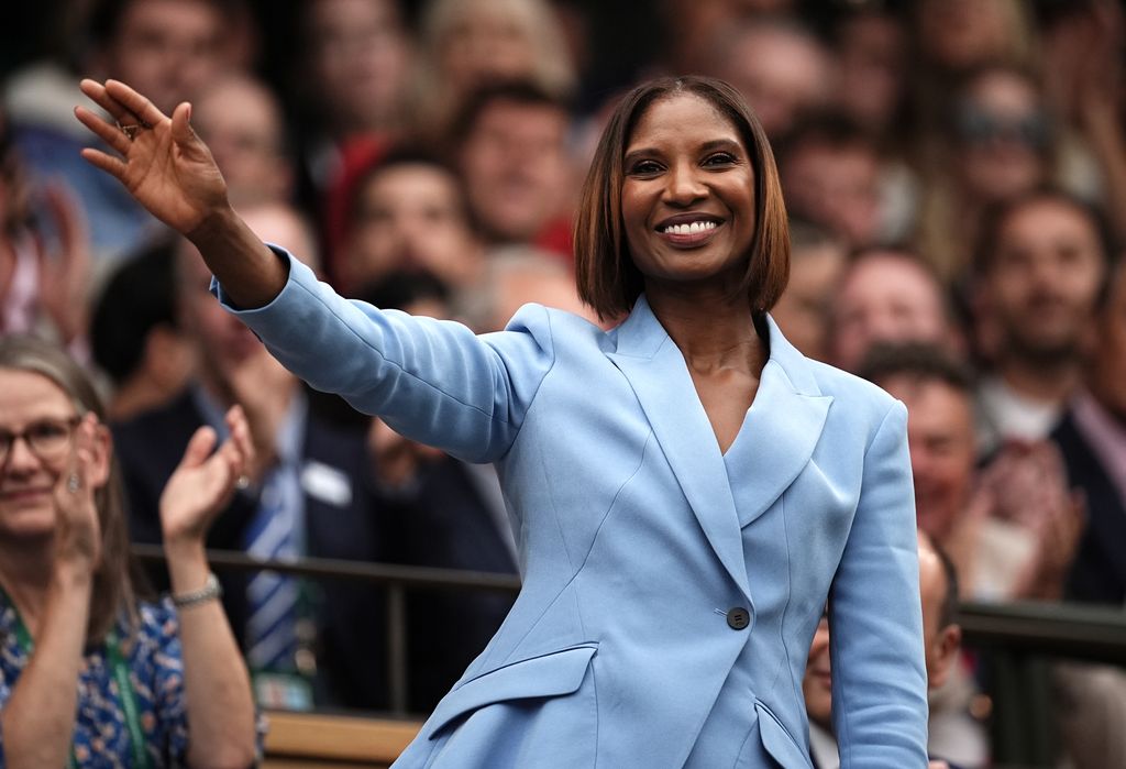 Denise Lewis waving in blue blazer