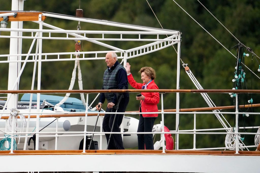 King Harald and Queen Sonja on board the Royal Yacht wave to the boats carrying wedding guests from Alesund to Geiranger