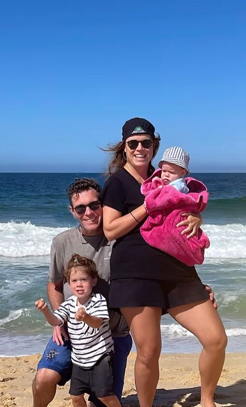 Princess Eugenie holding back Ernest while standing with Jack Brooksbank and son August