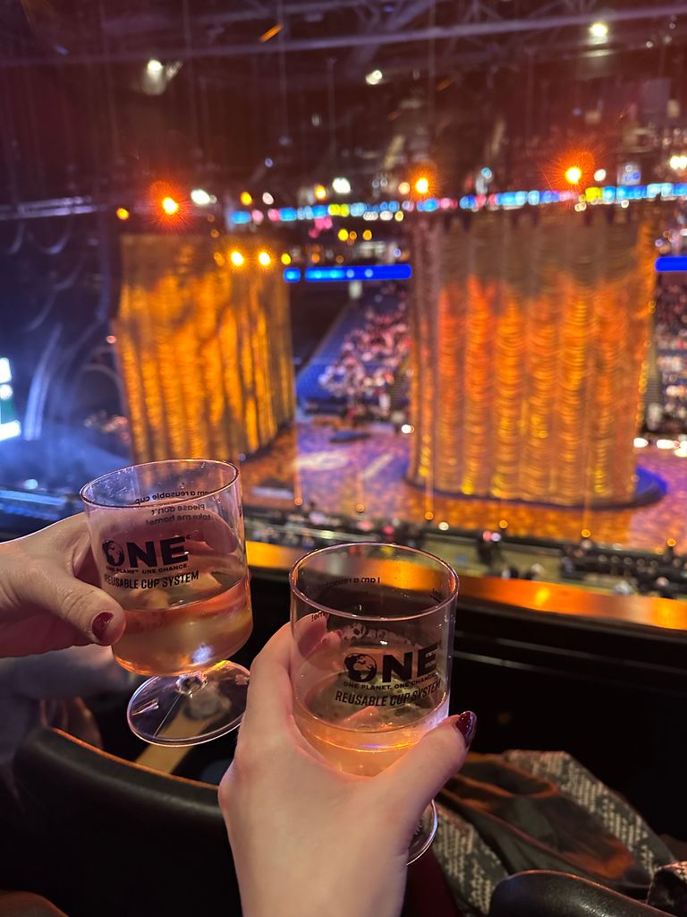 hands holding wine in front of stage