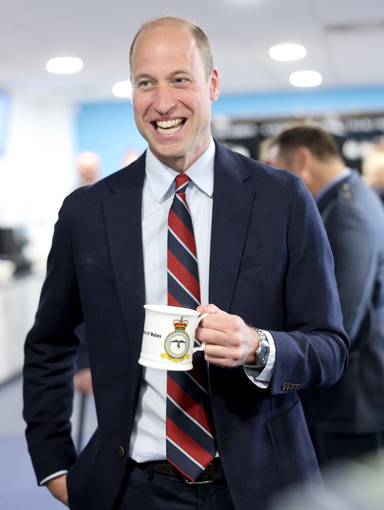 Prince William in a suit holding a mug