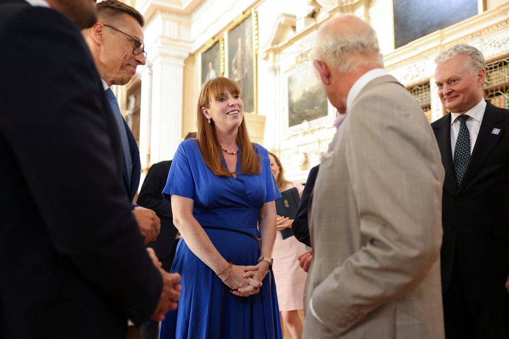 King Charles in a grey suit talking to Angela Rayner, who wears a blue dress