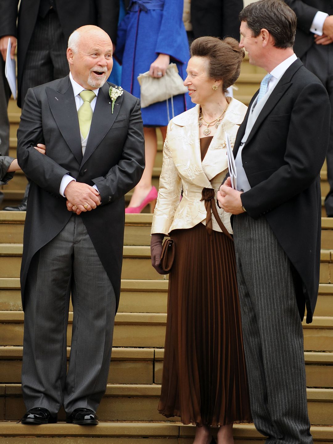 Princess Anne in a brown dress and white coat with Tim Laurence 