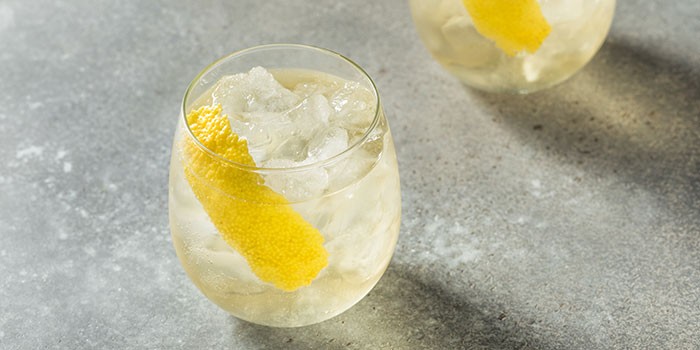 Glass of wine spritzer with ice and lemon peel