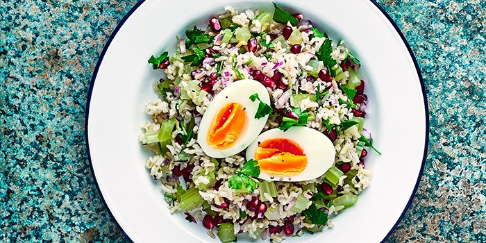 Brown rice tabbouleh with eggs & parsley on a blue table