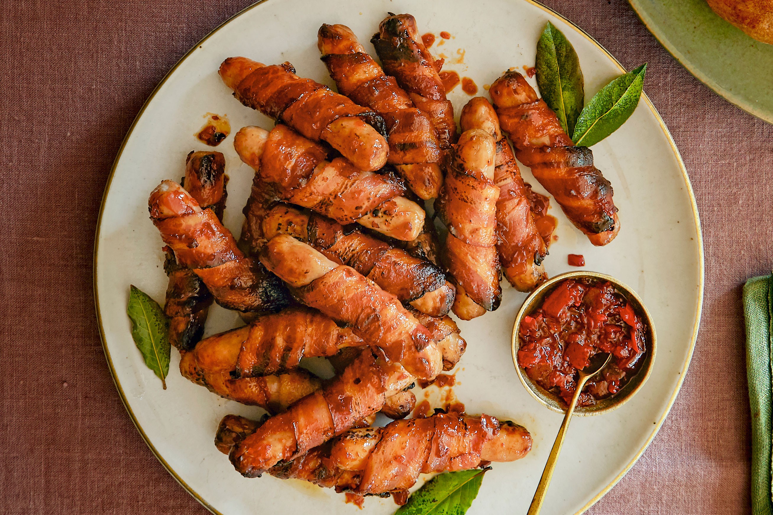 Sausages wrapped in bacon next to a sweet chilli dip