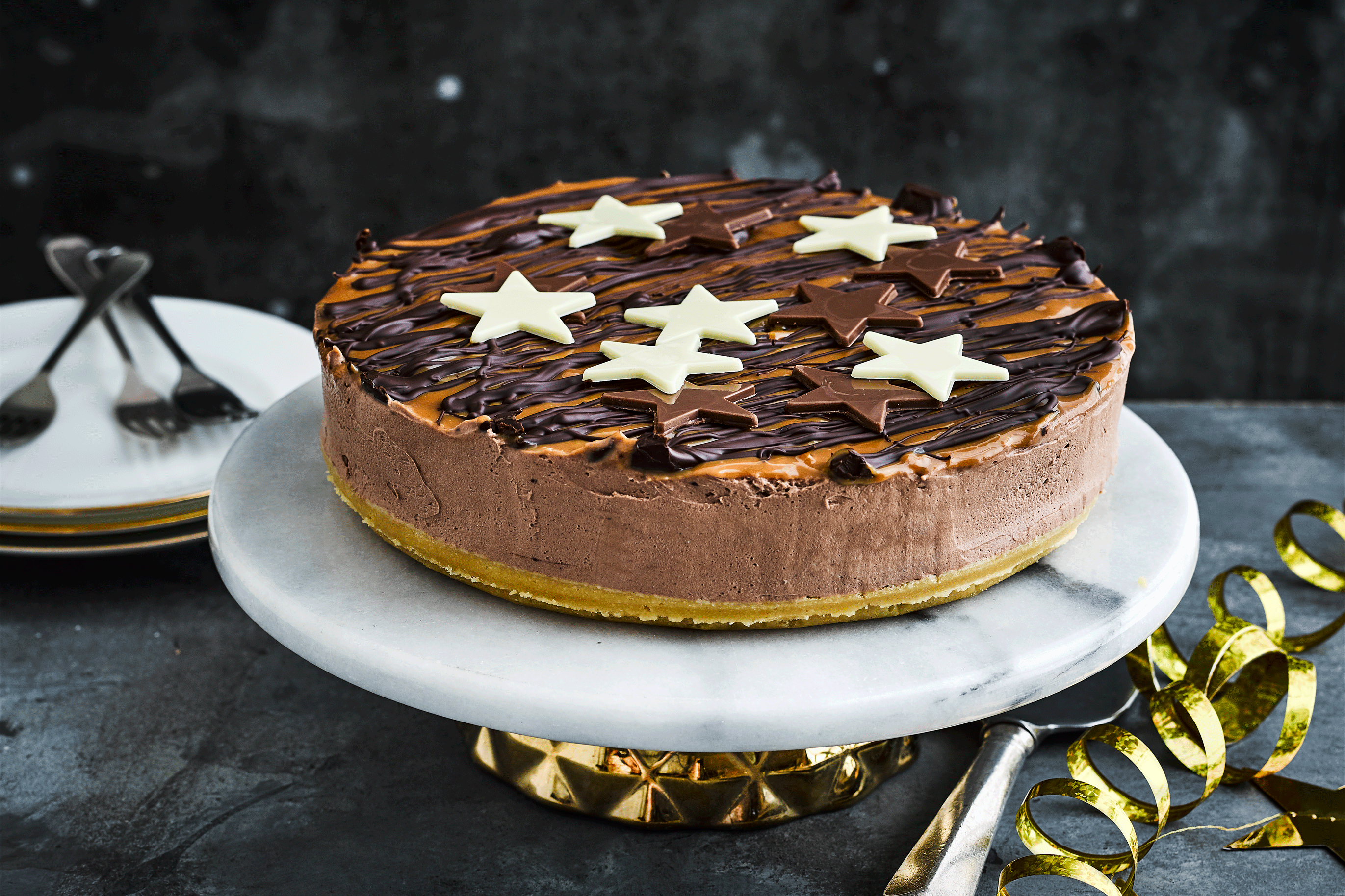 Millionaire's cheesecake white white and dark chocolate stars on a marble cake stand