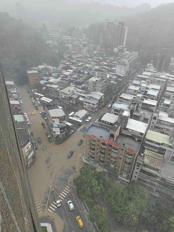 台北市吳興街公車總站的交叉路口則是可見黃泥水淹沒道路，不少車輛涉水通行或來不及挪移浸在突發的大水中。   圖：翻攝「臉書」信義區三兩事社團/邱詩喬