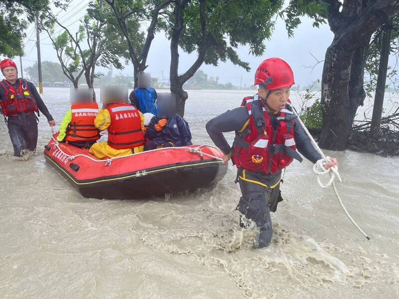 受颱風凱米影響，嘉義縣豪雨強風不減，25日雨勢持續且逢大潮，八掌溪水暴漲溢堤，消防人員協助民眾脫困。   圖：中央社/嘉義縣消防局提供