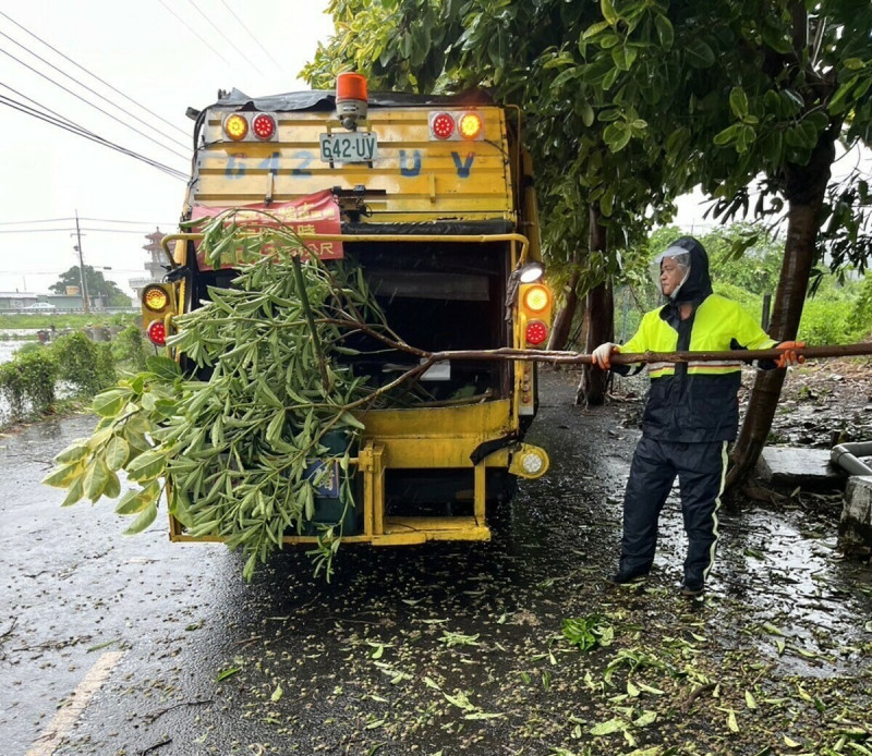 清潔隊人員冒風雨清理路上斷落的樹枝，保障行車安全。   圖：高雄市環保局/提供