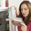 Une femme regarde la date de péremption d'un emballage de tranches de jambon cuit.