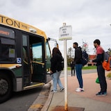 People line up at a bus stop.