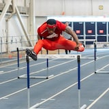 An action shot of Tamarri Lindo jumping over a hurdle during a competition.