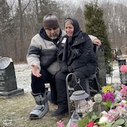 Une femme pleure et un homme lui parle, à côté de la tombe d'une des victimes de l'écrasement du vol PS752, dans un cimetière de Toronto.